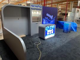 Custom Inline Exhibit with Backlit Fabric Graphics, Backlit Logo, Large Monitor Mount, Puck Lights, Backwall Locking Storage, (3) Shelves, MOD-1573 Counter, Product Display, and Corral Walls with Graphics